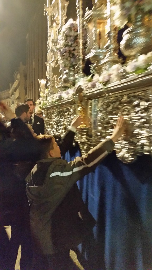 As the holy image passes by, the people in the crowd would reach out to touch it and make the sign of the cross.