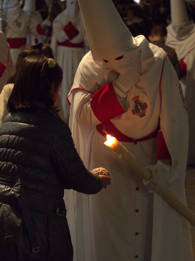 Children make wax balls from the penitents' candles, some of the penitents are not much older than the children making the balls.