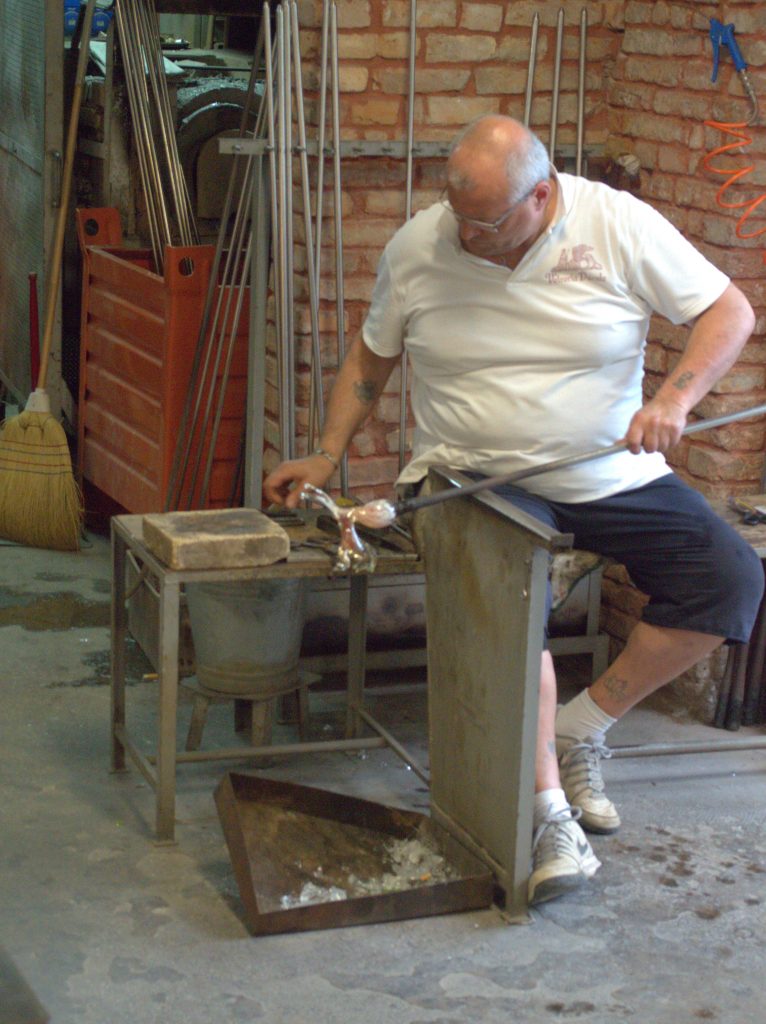 A Venetian glass-maker in action. Notice that he's not wearing any gloves or other safety gear for handling hot stuff.