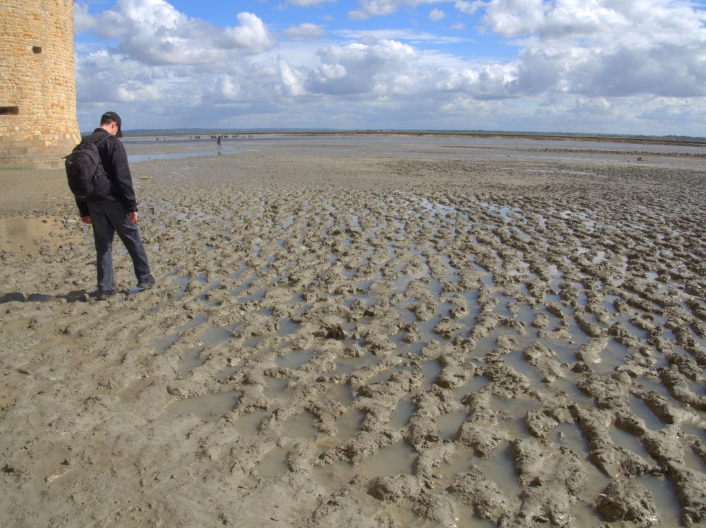 Pedr attempting to walk across the mud (while still wearing shoes).