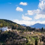 A picture of the Generalife and its gardens sitting on a hill with the snow-covered Sierra Nevada mountains in the background.