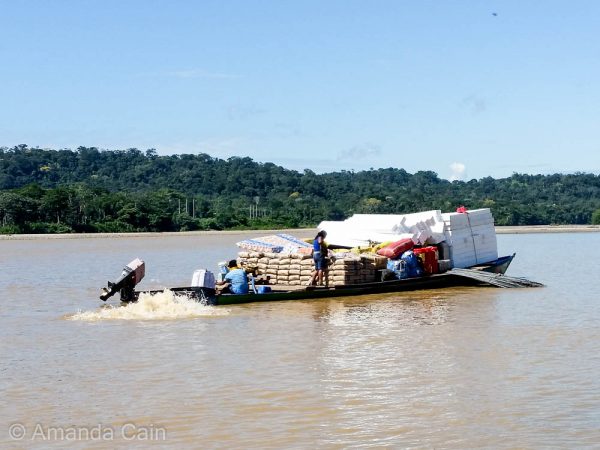 A jungle "cargo ship" struggling to make its way along the river. It's actually two regular boats held together by the weight of all the cargo.