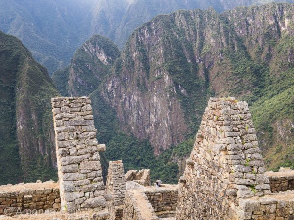 Machu Picchu is built on a steep sided mountain surrounded by more steep sided mountains.