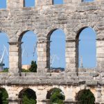 Old and new: the Ancient Roman amphitheatre and the modern port cranes of Pula.