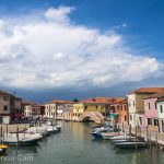 Storm clouds gather over a sunny Venetian canal.