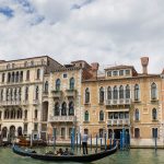 A typical scene in Venice; a gondola with tourists sailing down the Grand Canal.