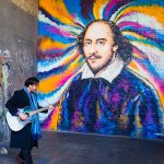 A busker in front of a newly painted Shakespeare mural.