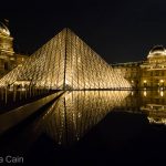The glowing Main Pyramid of the Louvre reflected in the perfectly still fountain waters.