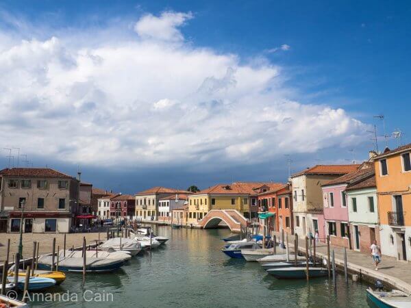 Storm clouds gather over a sunny Venetian canal.