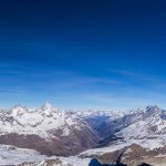 A panoramic view of the Swiss Alps with the Matterhorn on the far left, the town of Zermatt nestled in the valley in the centre, and the Breithorn on the right.